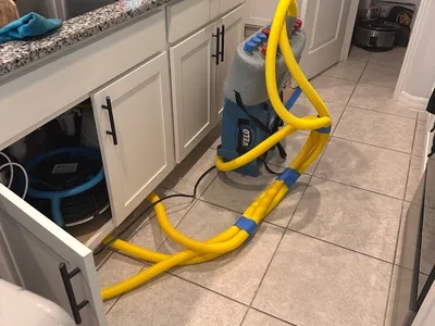 Water extraction setup with blue machine and yellow hose inside cabinetry area